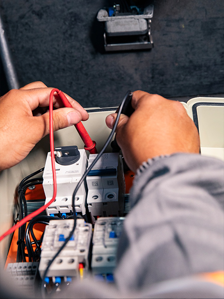 Técnico medindo tensão e conexões em painel elétrico com multímetro — diagnóstico e manutenção de painéis elétricos industriais