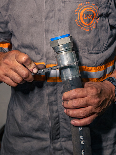 Técnico apertando conexão em mangueira com chave — inspeção e montagem de conexões hidráulicas e pneumáticas