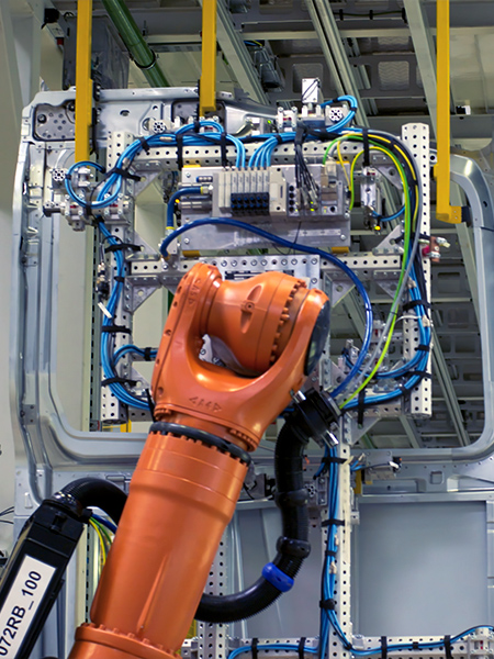 Robô industrial laranja em célula de automação com cabeamento e painéis elétricos visíveis — automação industrial