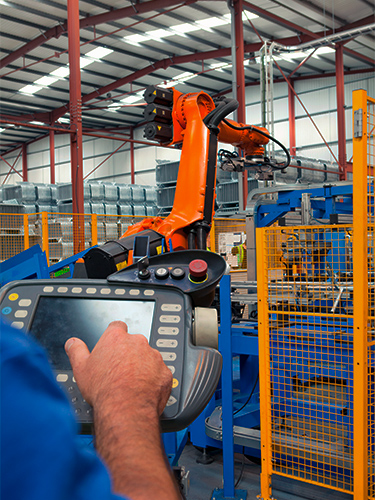 Operador usando controlador manual (pendant) para programar e controlar robô industrial em linha de produção — automação industrial