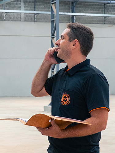 Engenheiro em campo falando ao celular e segurando pasta com documentação técnica — coordenação da consultoria em sistemas pneumáticos